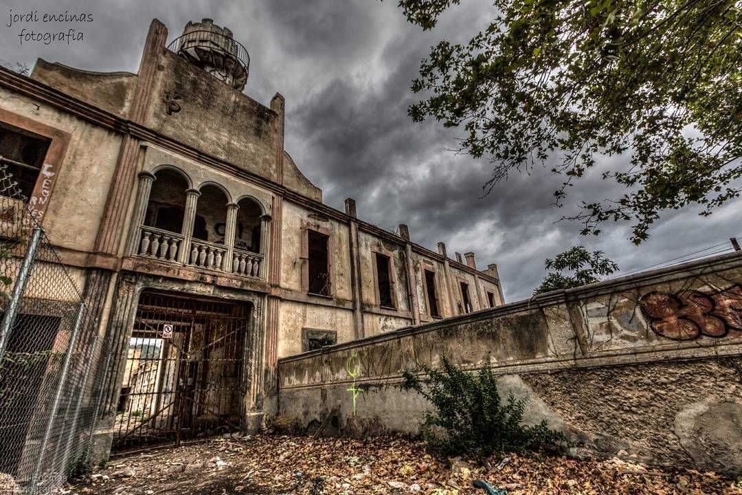 Un viejo edificio abandonado con grafitis en la pared y un cielo nublado al fondo.