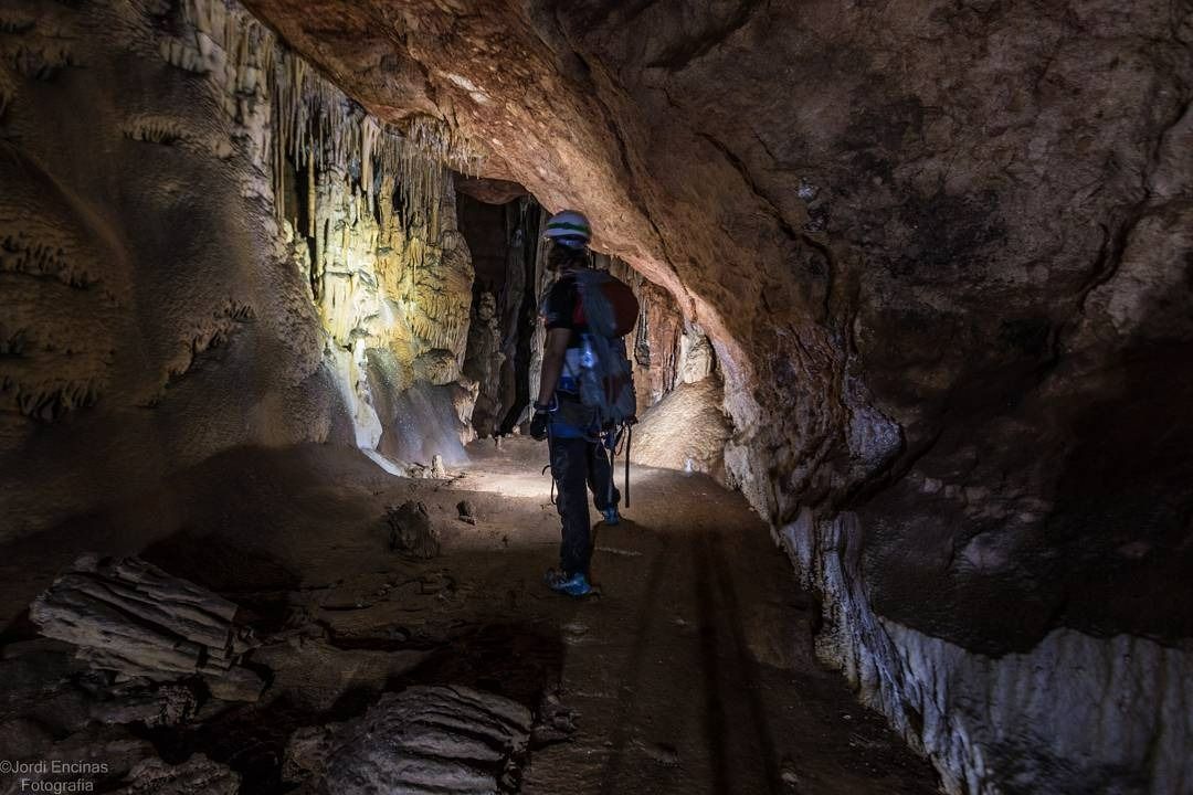 Una persona camina por una cueva con una linterna.