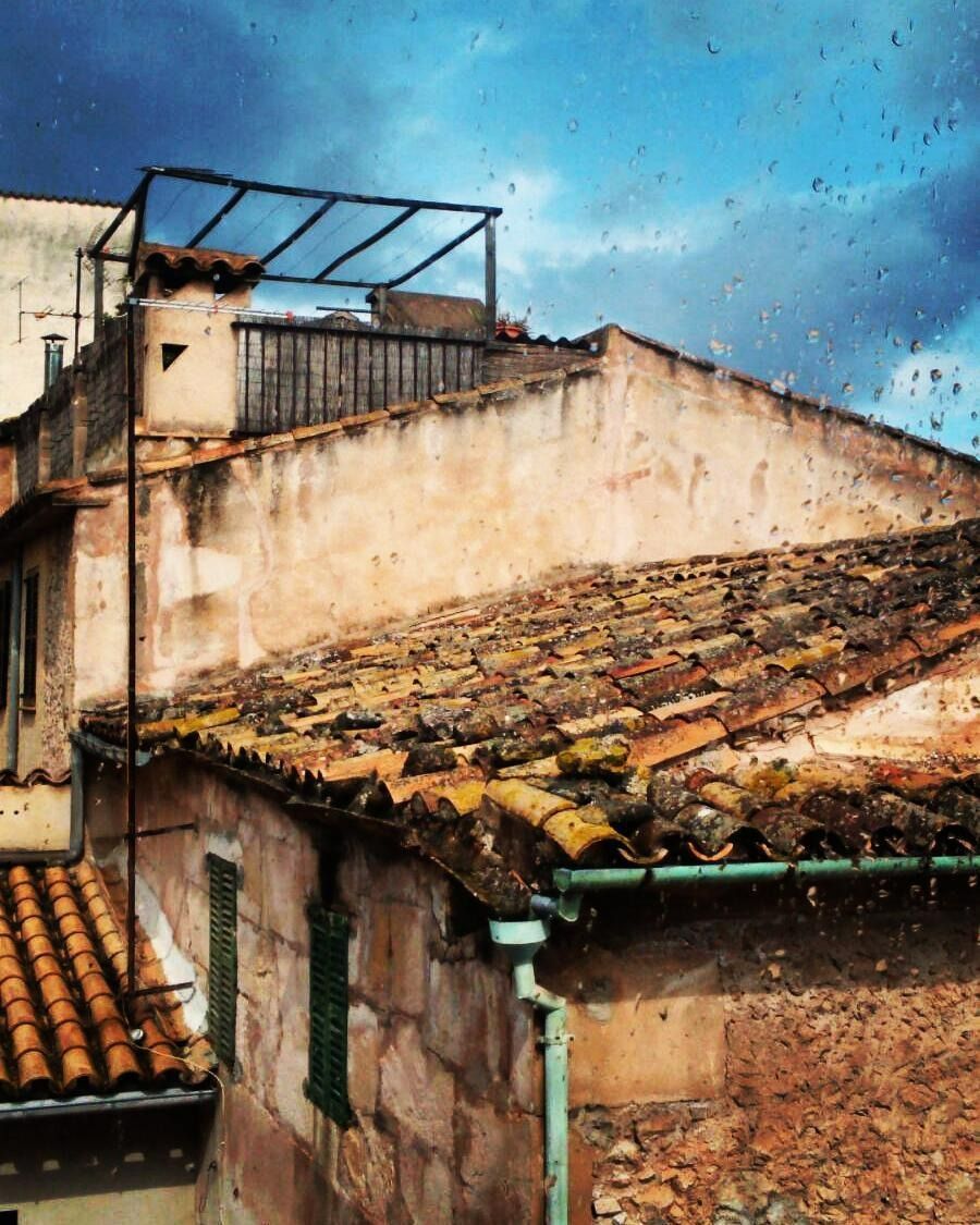 Un edificio con techo de tejas y un balcón en la parte superior.