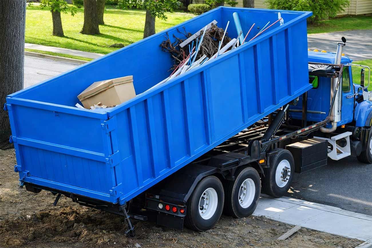 Camión cargando chatarra en un contenedor grande.