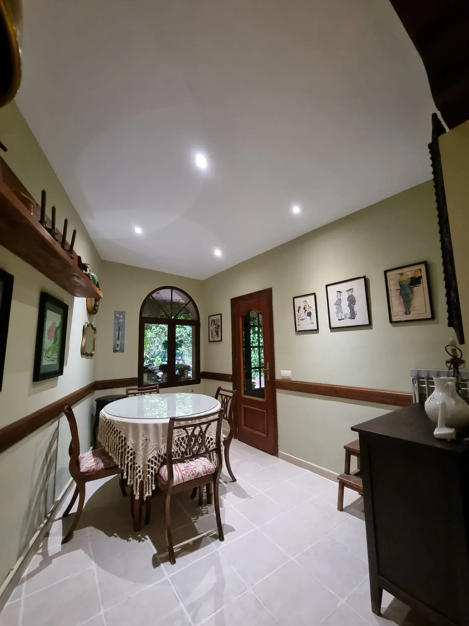 Un rincón de comedor con una mesa redonda, cuatro sillas ornamentadas