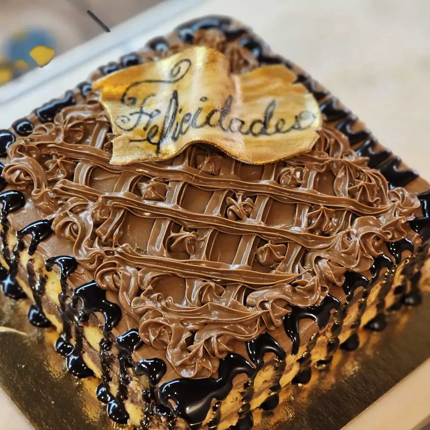 Un pastel de chocolate con la palabra felicidades escrita en él.