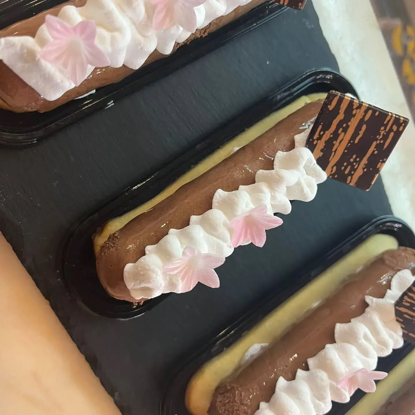 Una fila de postres con crema batida y flores encima.