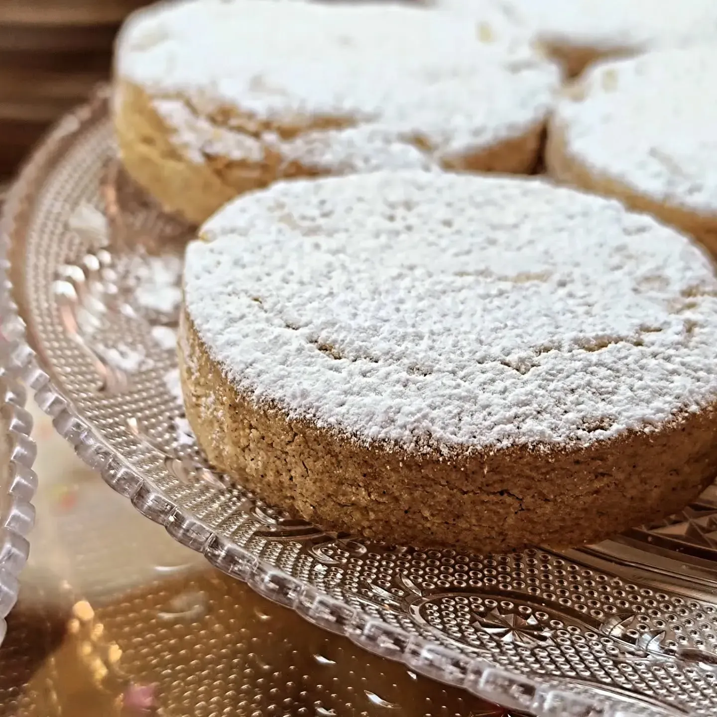 Un primer plano de un pastel con azúcar en polvo sobre un plato de vidrio.