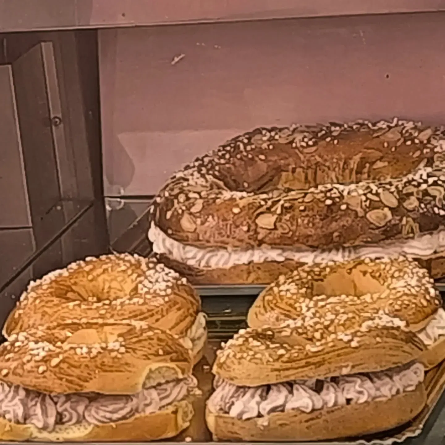 Una variedad de pasteles se exhiben en un estante de vidrio.