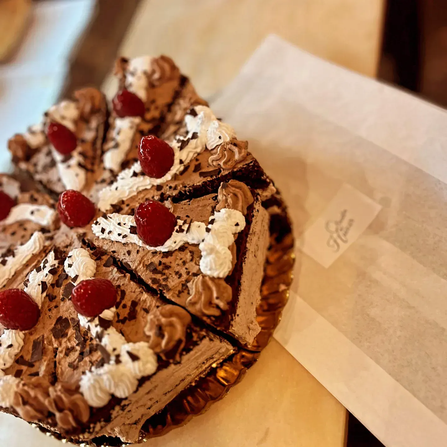 Un pastel de chocolate con frambuesas y crema batida encima.