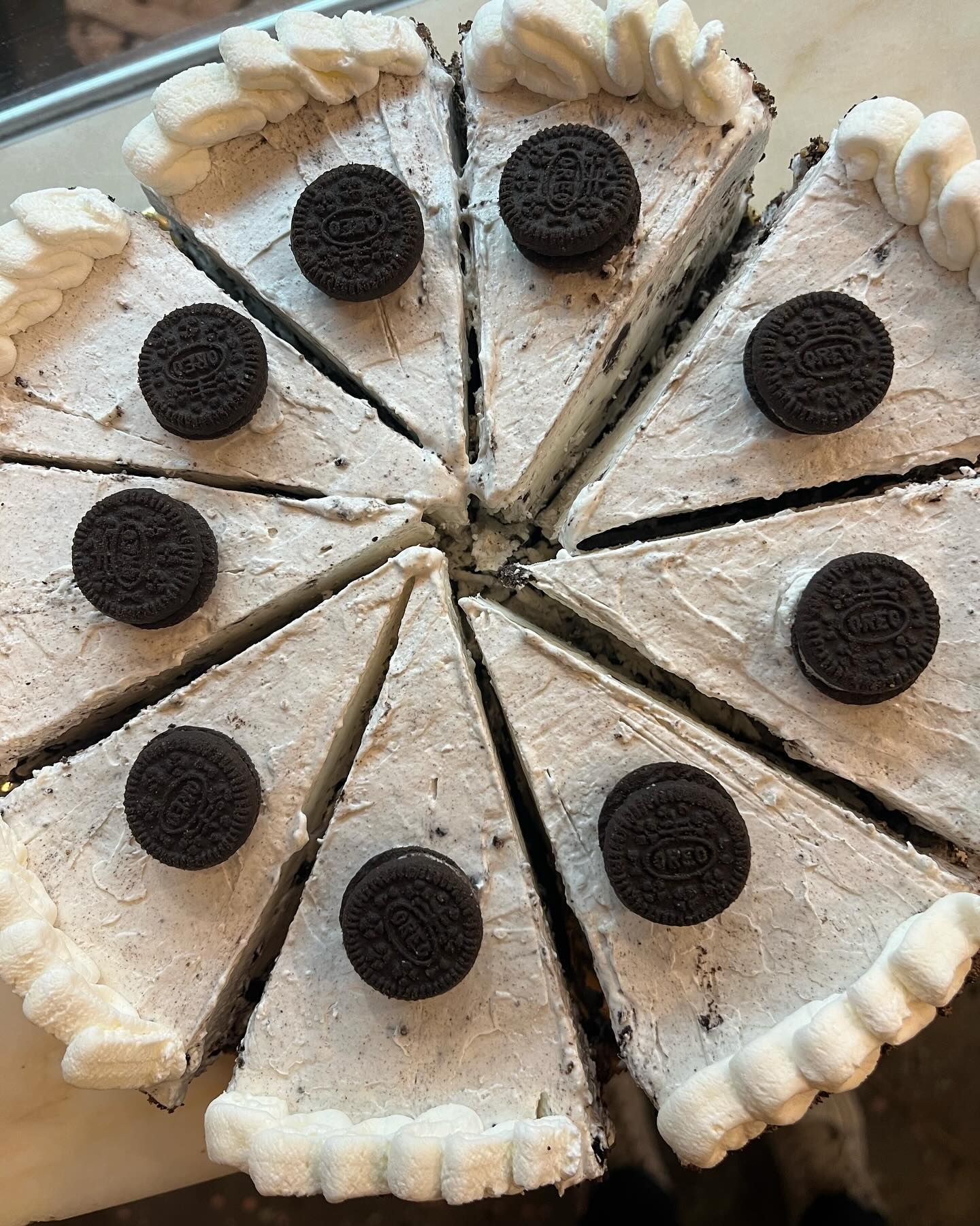 Una rebanada de tarta de queso Oreo con crema batida y Oreos encima.