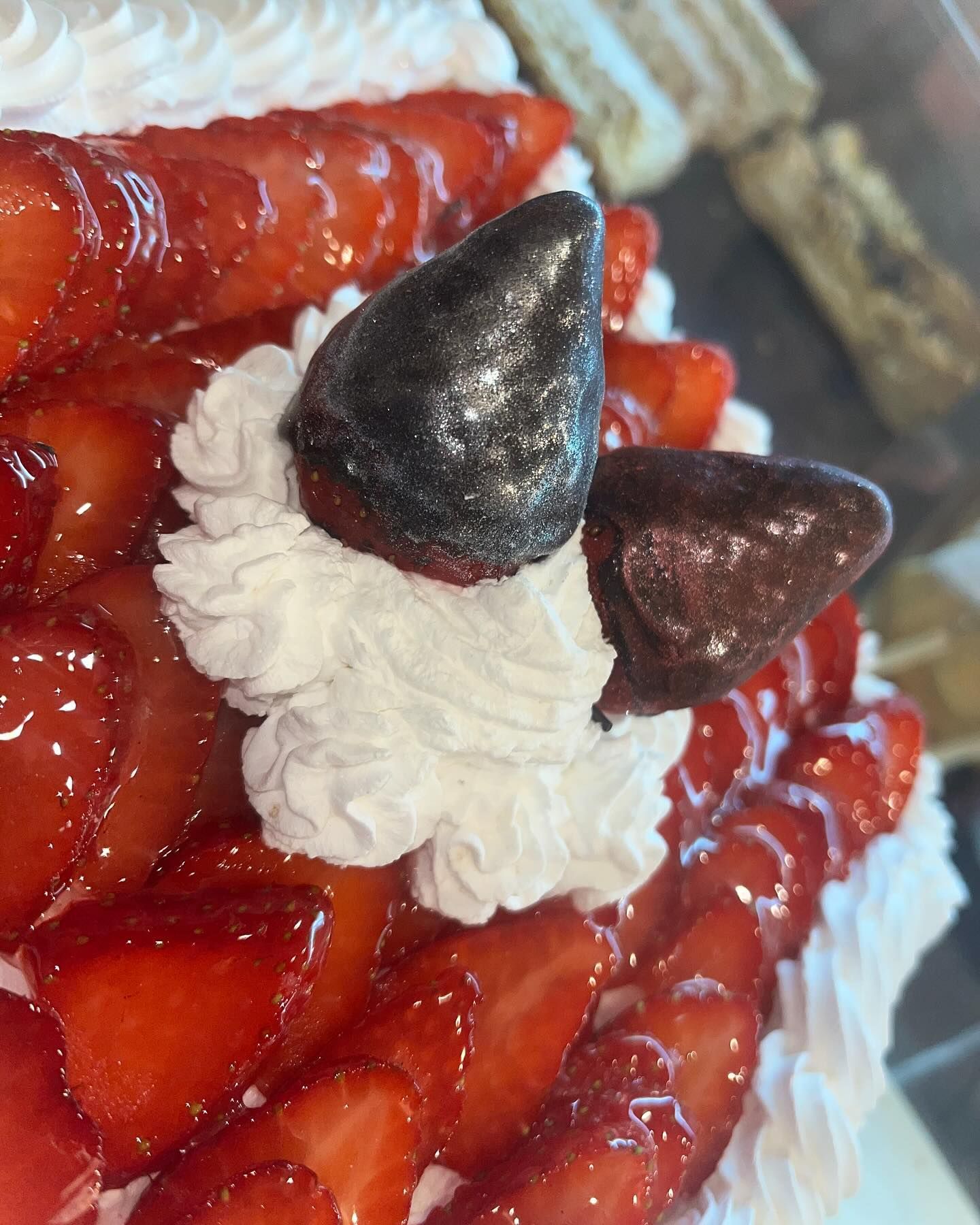 Un primer plano de un pastel con fresas y crema batida.