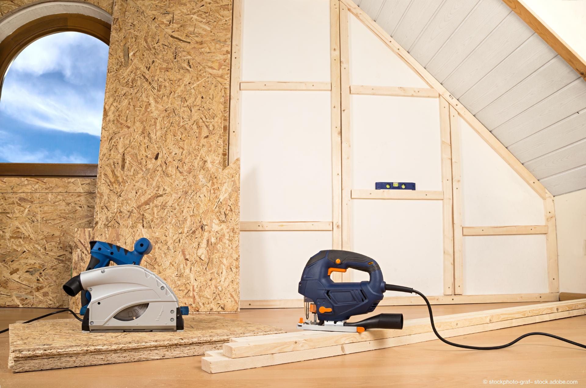 Die Werkzeuge für die Holzbearbeitung liegen auf einem Holzboden in einem Raum mit einem Bogenfenster und unfertigen Wänden.