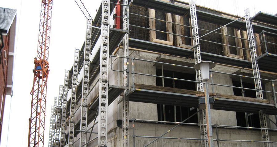 Ein großes Gebäude im Bau mit Gerüsten und einem Kran im Hintergrund