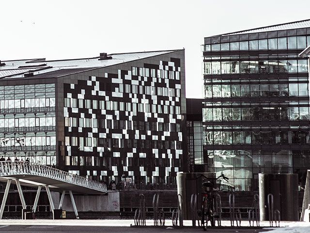 Ein Schwarzweißfoto eines großen Gebäudes mit einer Brücke davor.