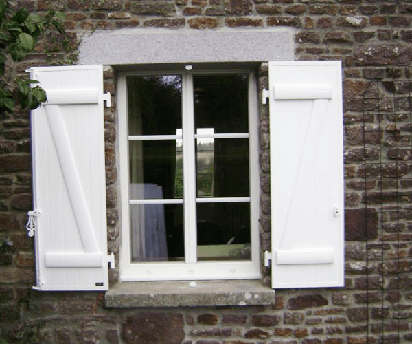 Volets blancs sur un mur en pierre