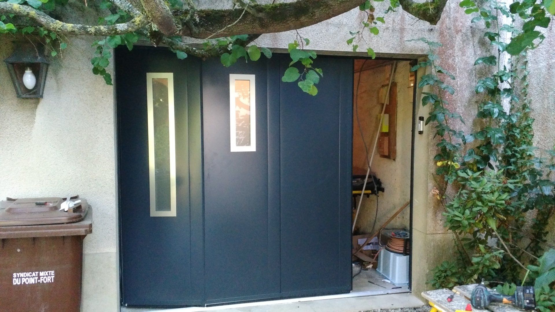 Porte de garage coulissante bleue en cours d'ouverture