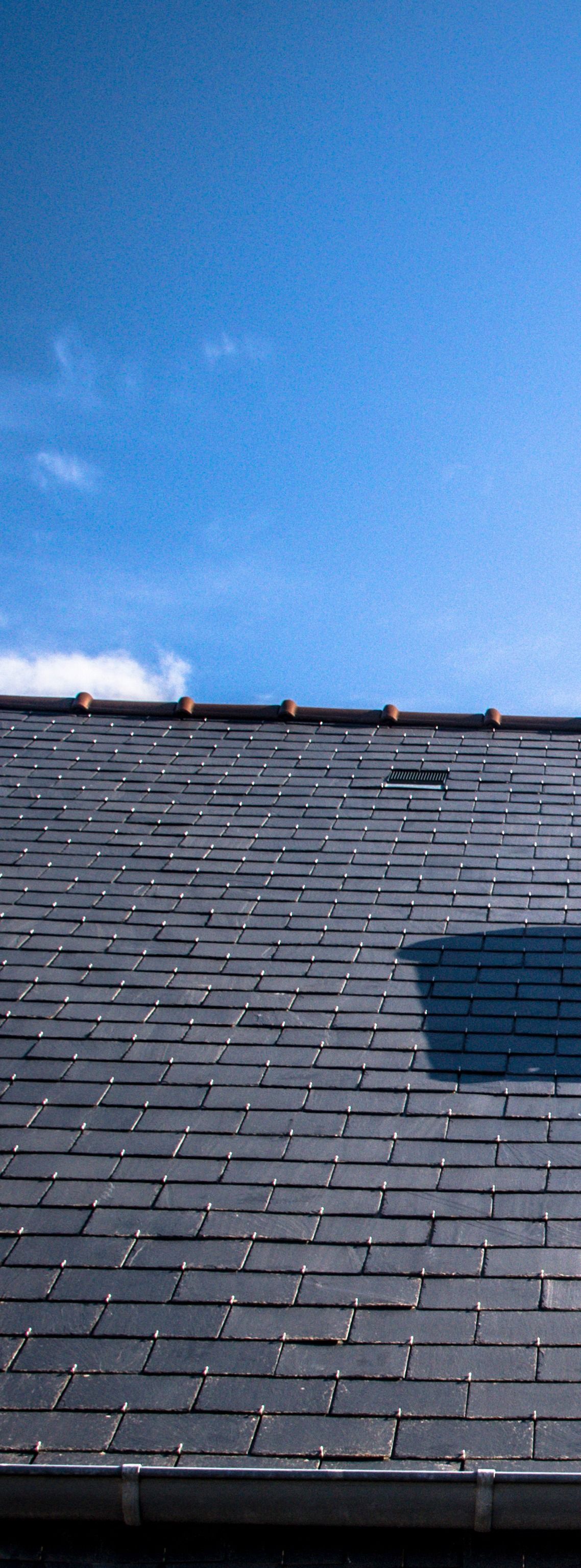 Toit en ardoise contre un ciel bleu.