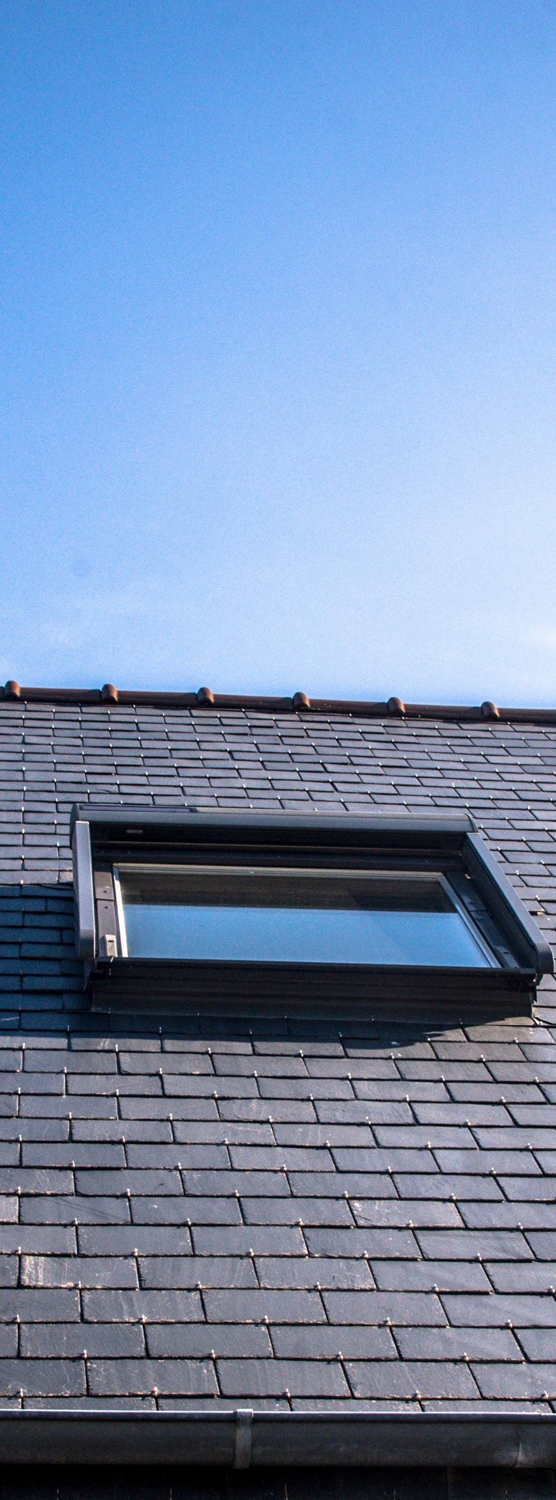 Toit en ardoise et ciel bleu vif.