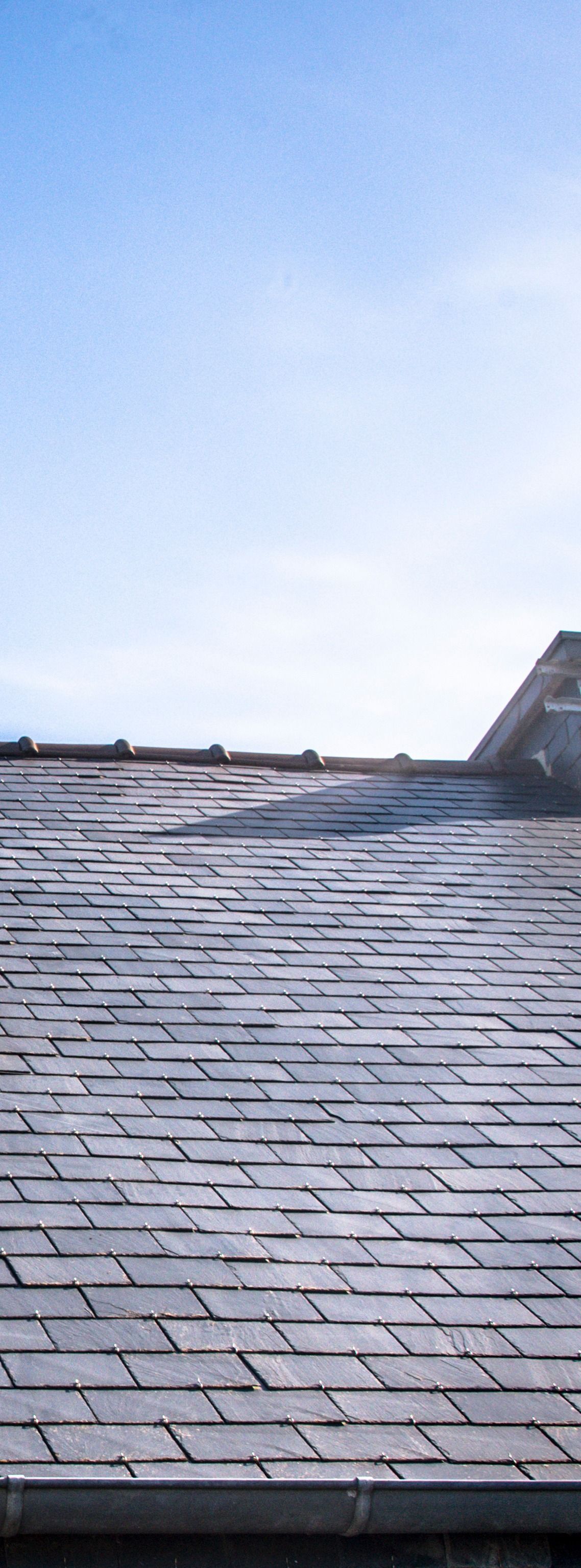 Toit en ardoise contre un ciel bleu.