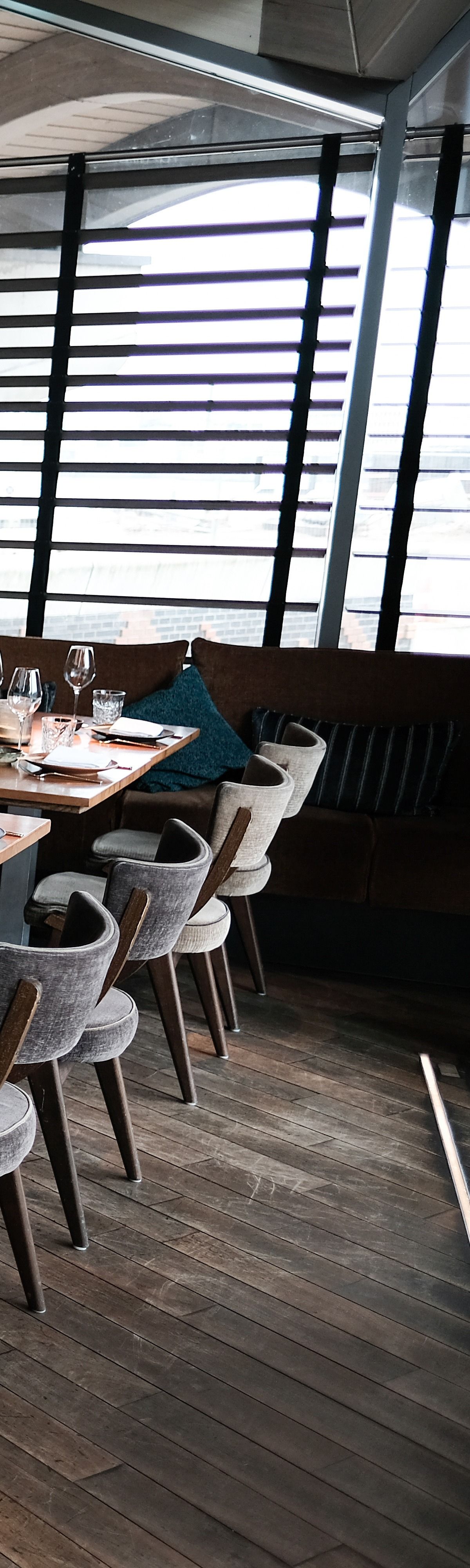 Intérieur du restaurant avec parquet, tables avec couverts et chaises.