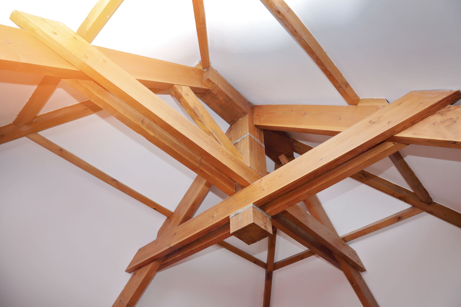 Chevrons en bois formant une structure contre un plafond blanc, vu d'en bas.