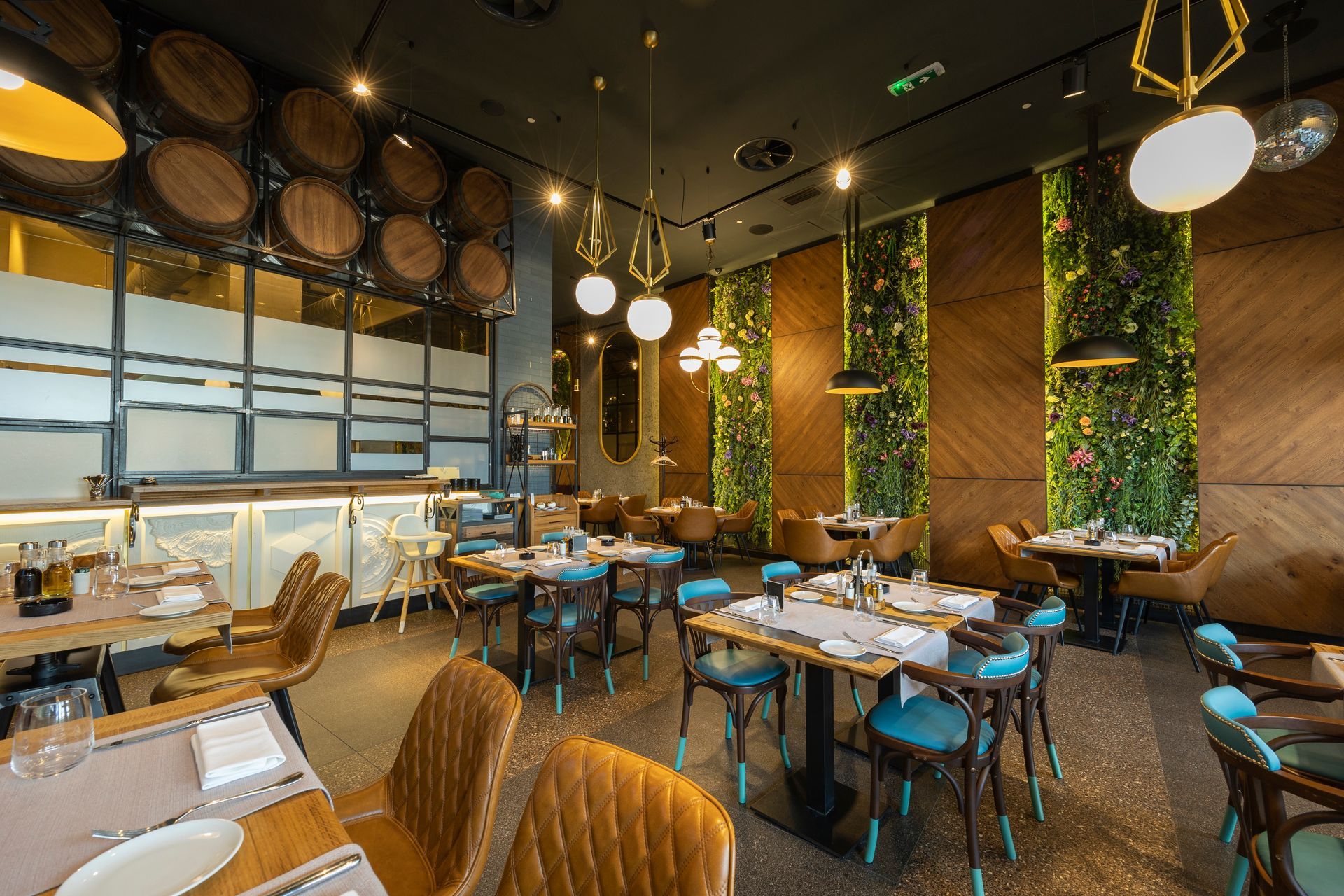 Intérieur de restaurant avec des murs en bois, une décoration végétale et des chaises bleues.