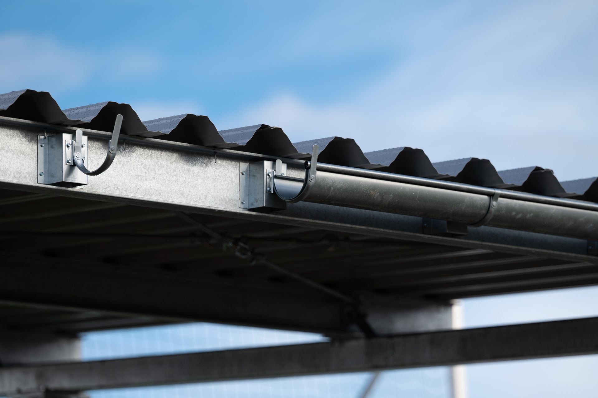 Toiture en tôle ondulée avec gouttière partiellement posée.