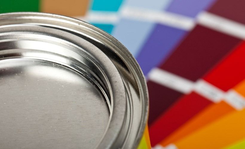 Una lata de pintura está delante de una paleta de colores de pintura.