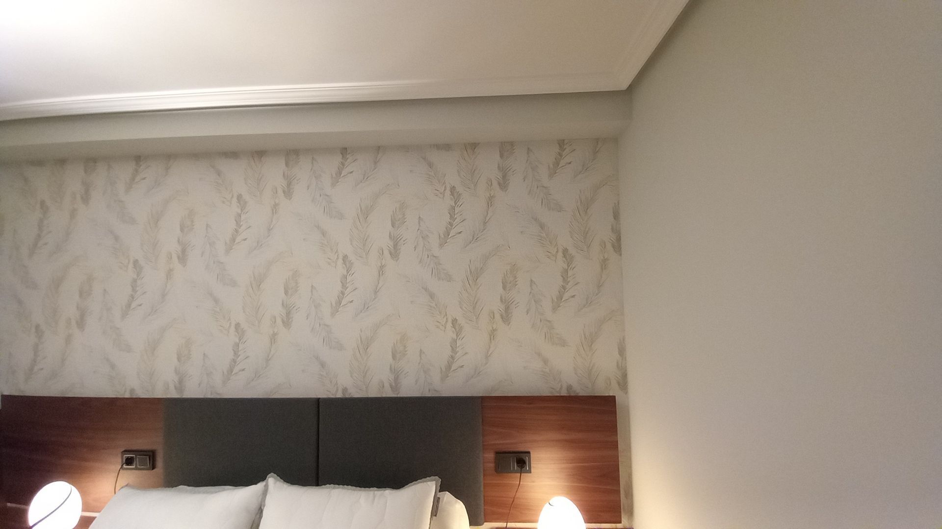 Una habitación de hotel con una cama, lámparas y una pared de mármol.