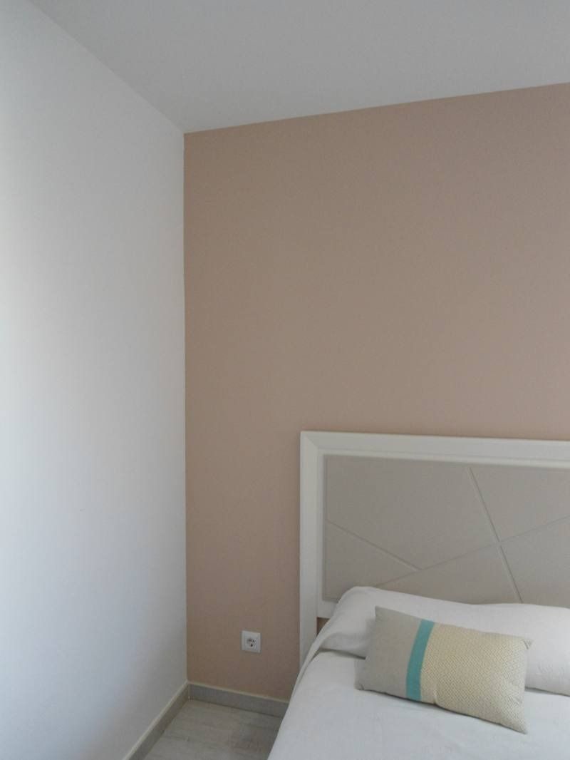 Un dormitorio con una cama y una pared rosa.