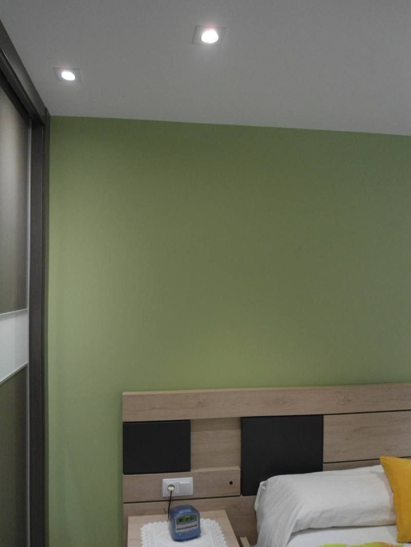 Un dormitorio con cama, mesita de noche y paredes verdes.