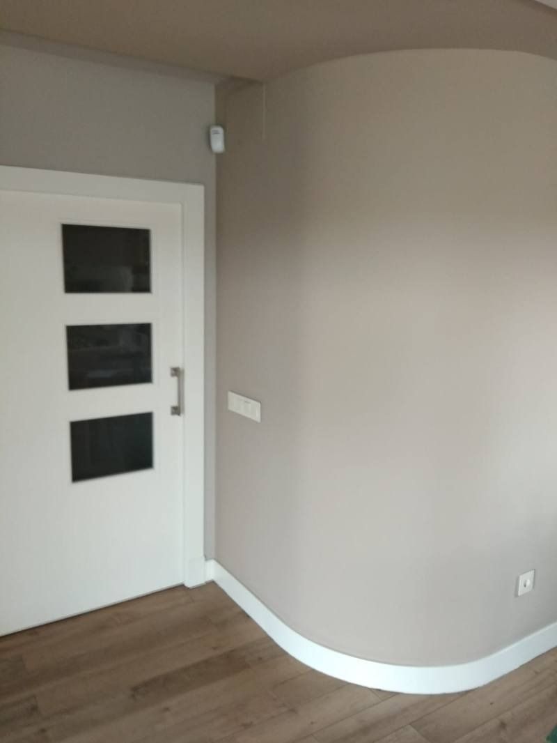 Una habitación con una pared curva y una puerta blanca con tres ventanas.