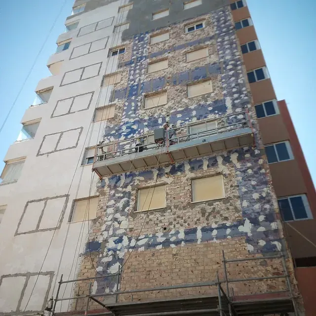 Un edificio alto con muchas ventanas y andamios a su alrededor.
