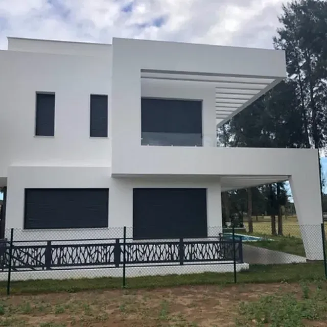 Una gran casa blanca con una valla negra alrededor.