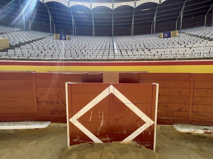 Un estadio vacío con una valla roja y un diamante sobre ella.