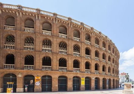 Un gran edificio de ladrillo con arcos y balcones en un día soleado.