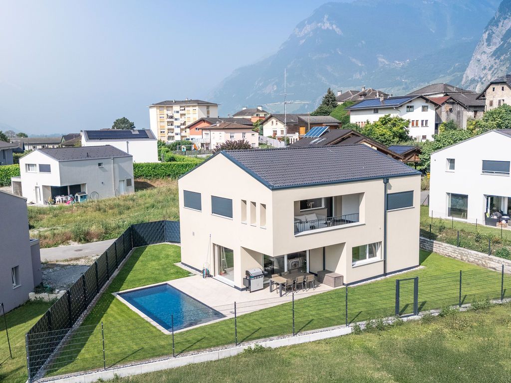 Maison moderne avec piscine et vue sur les montagnes. Pelouse verdoyante, piscine bleue, façade claire.