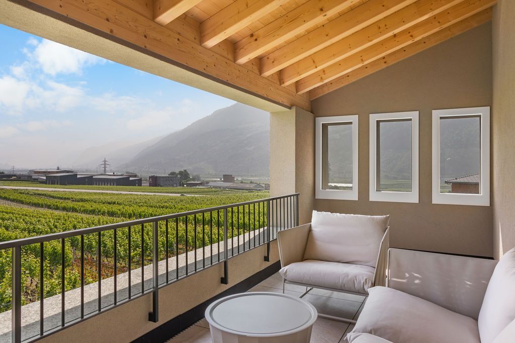 Maison moderne beige avec piscine, terrasse et vue sur les montagnes.