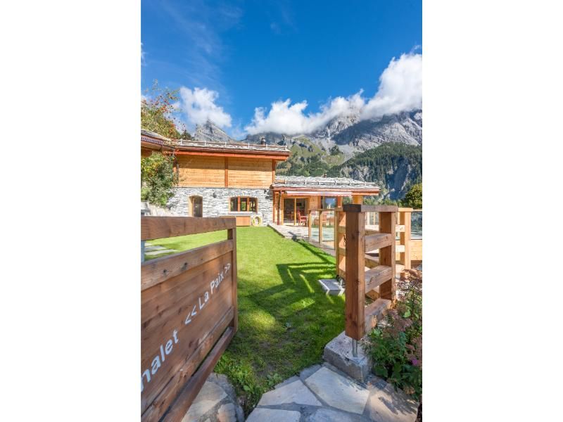 Une clôture en bois entoure une maison avec des montagnes en arrière-plan.