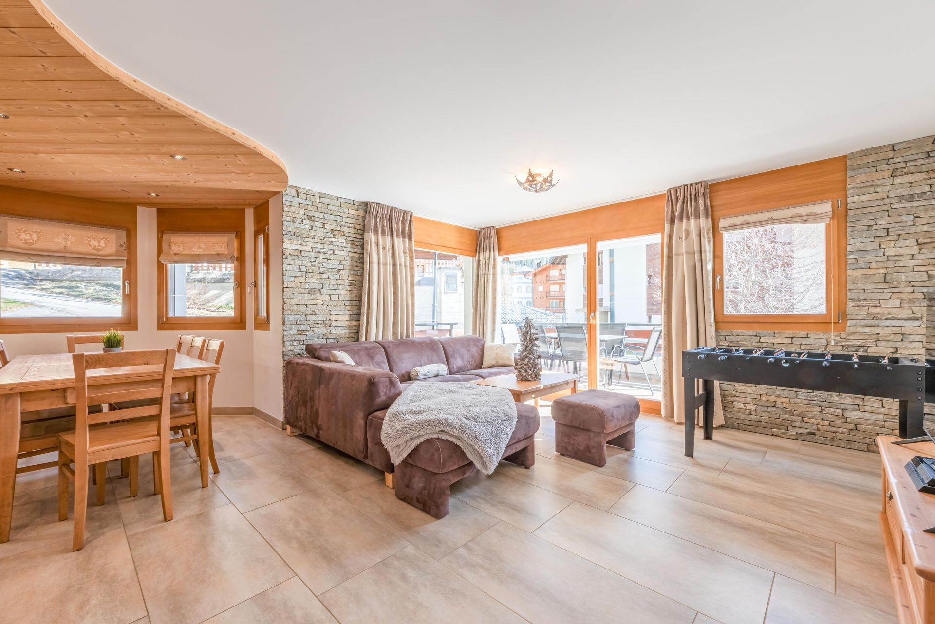 Un salon avec un canapé, une table, des chaises et un baby-foot.