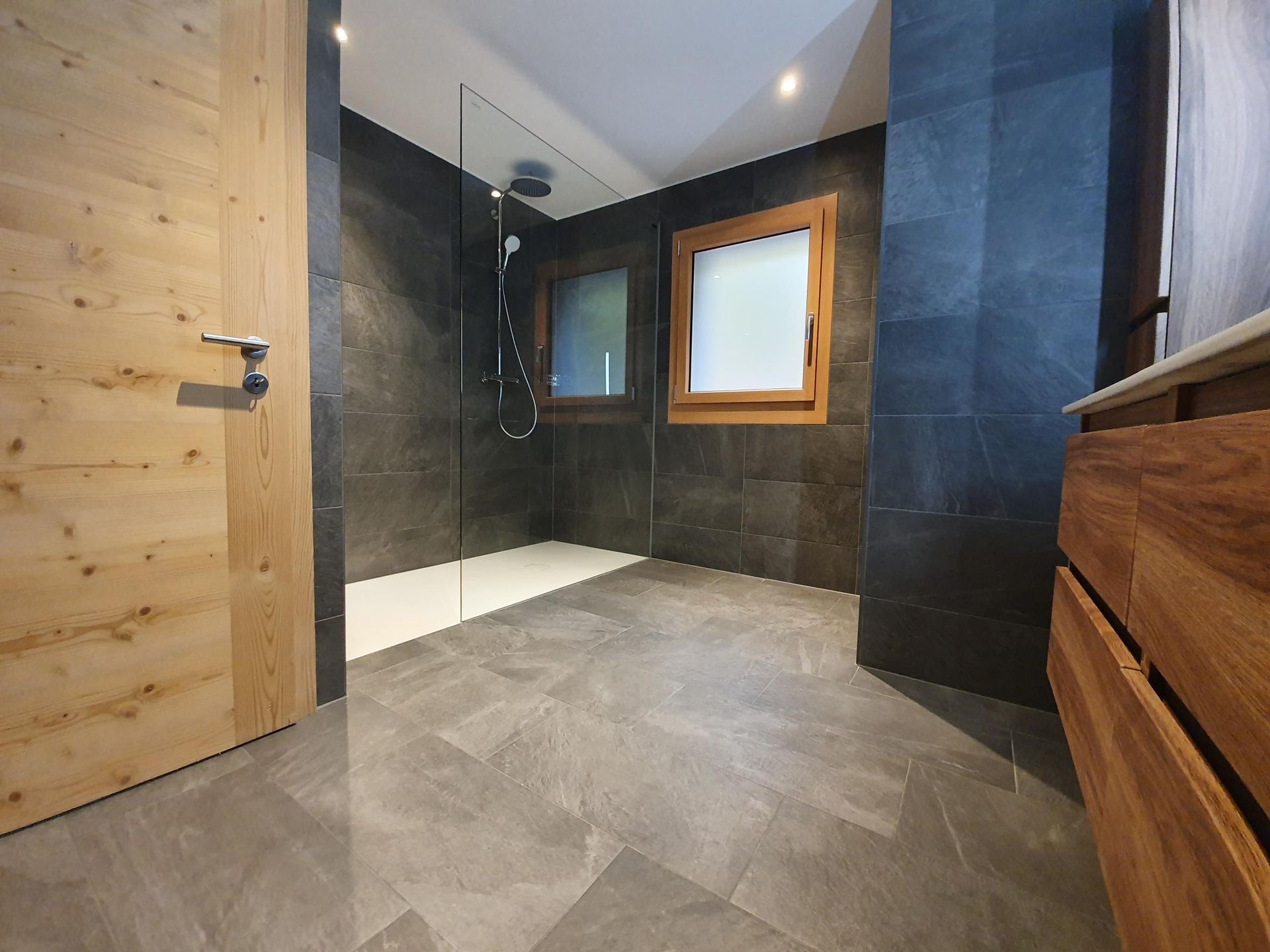 Une salle de bain avec une douche à l'italienne et une porte en bois
