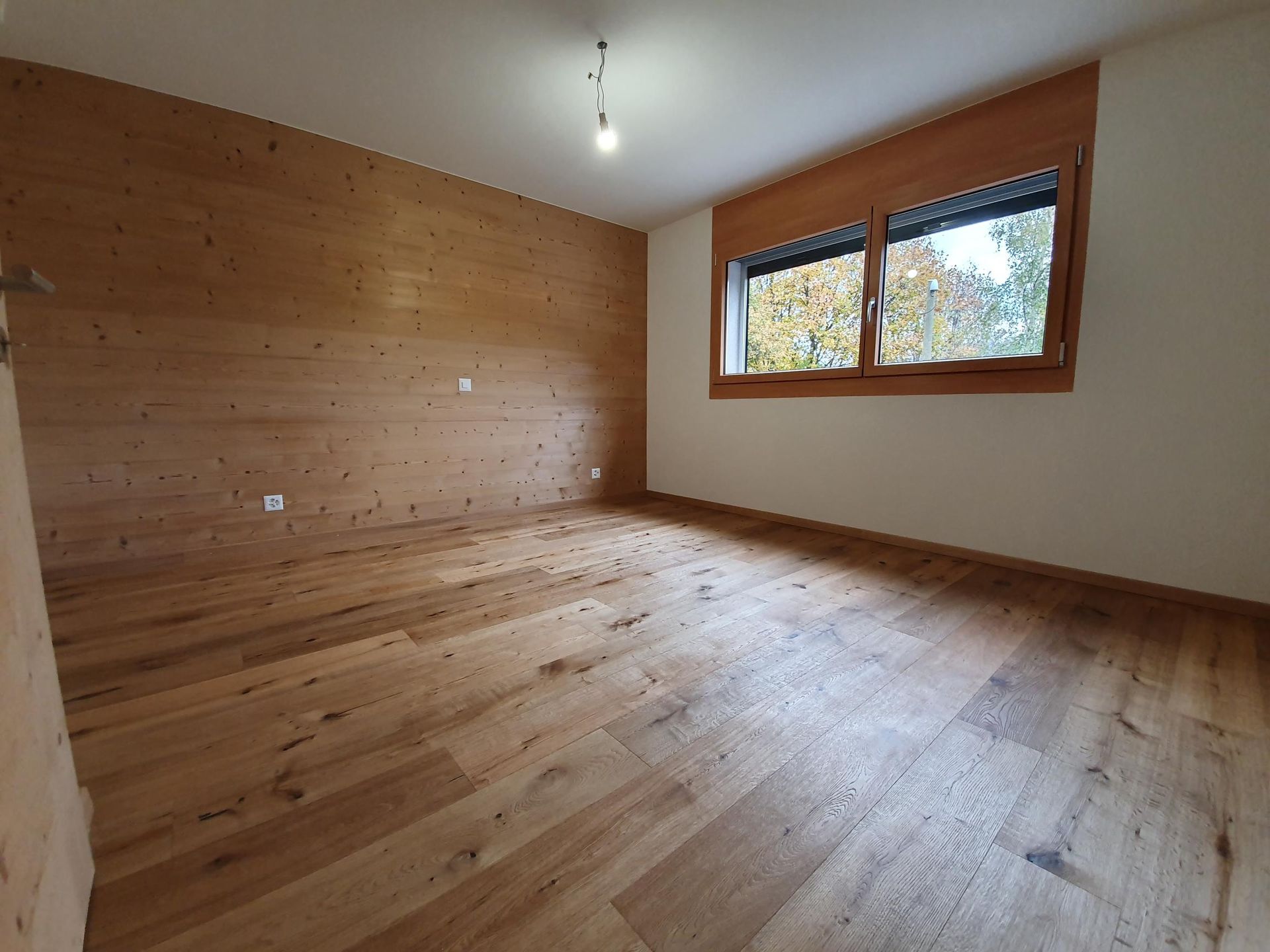 Une pièce vide avec du parquet et des murs en bois