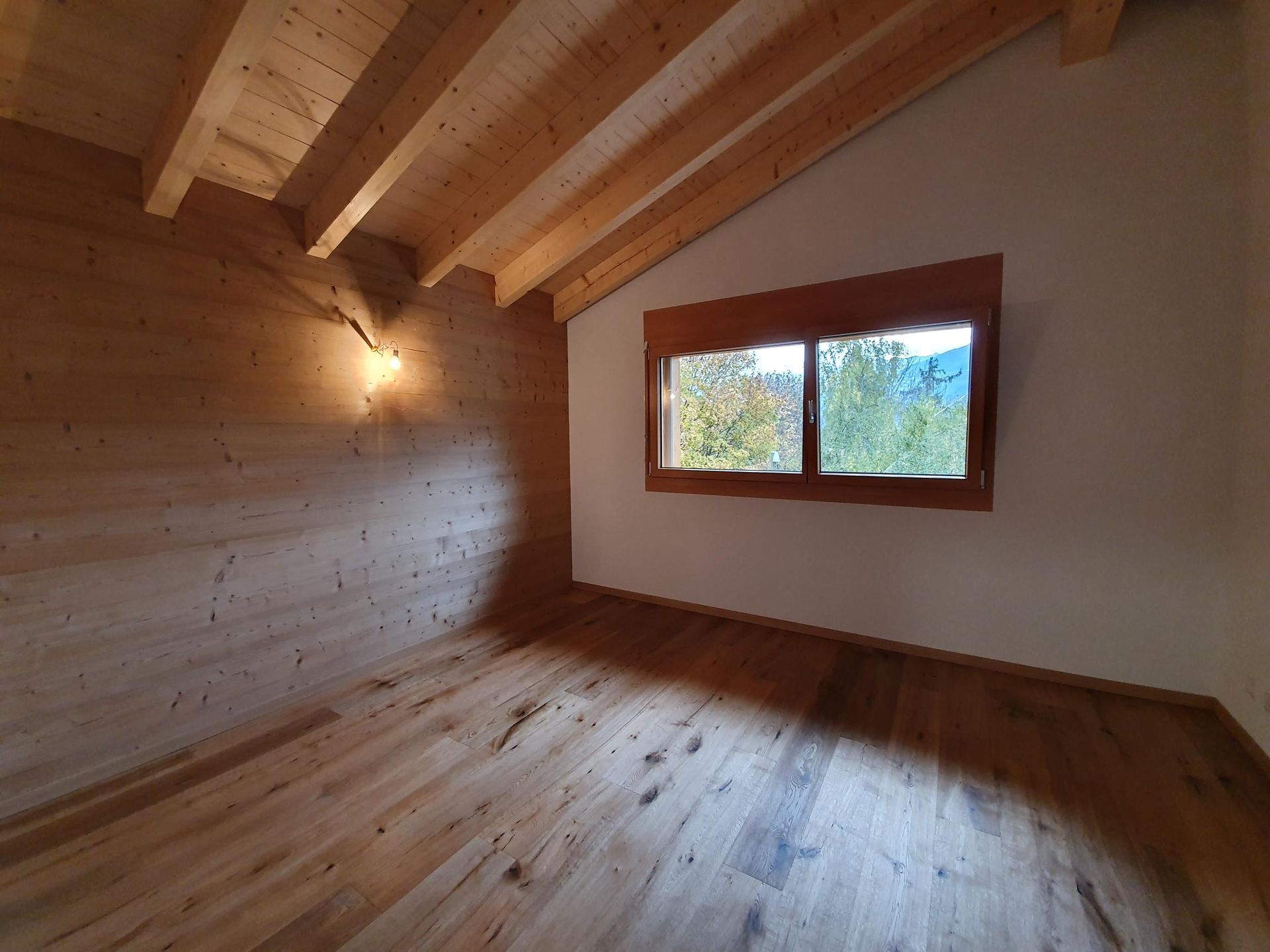 Une pièce vide avec du parquet et une fenêtre