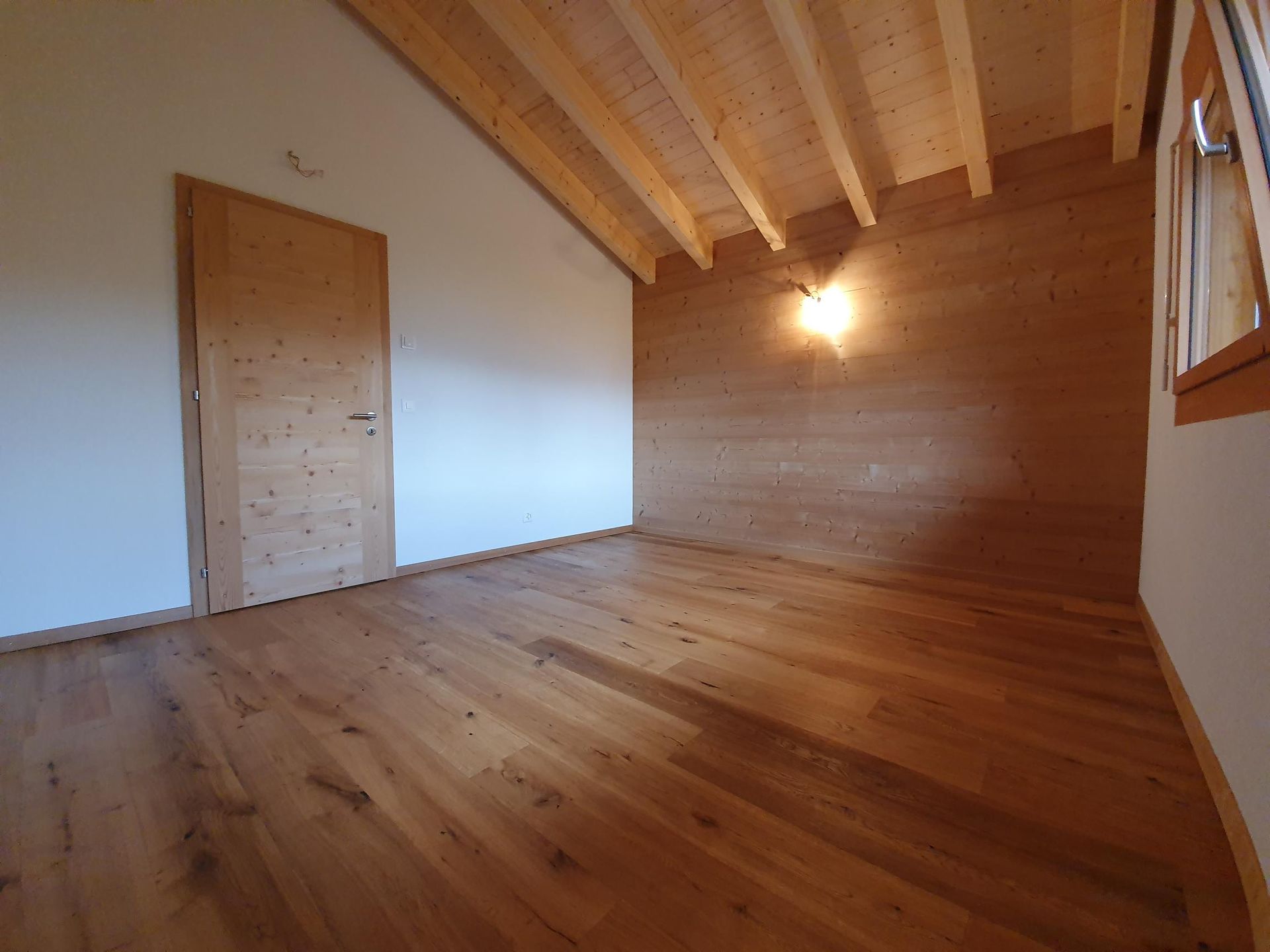 Une pièce vide avec du parquet et une porte en bois.