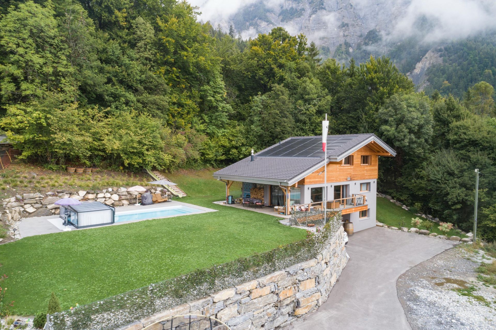 Une vue aérienne d'une maison avec piscine au milieu d'une forêt.
