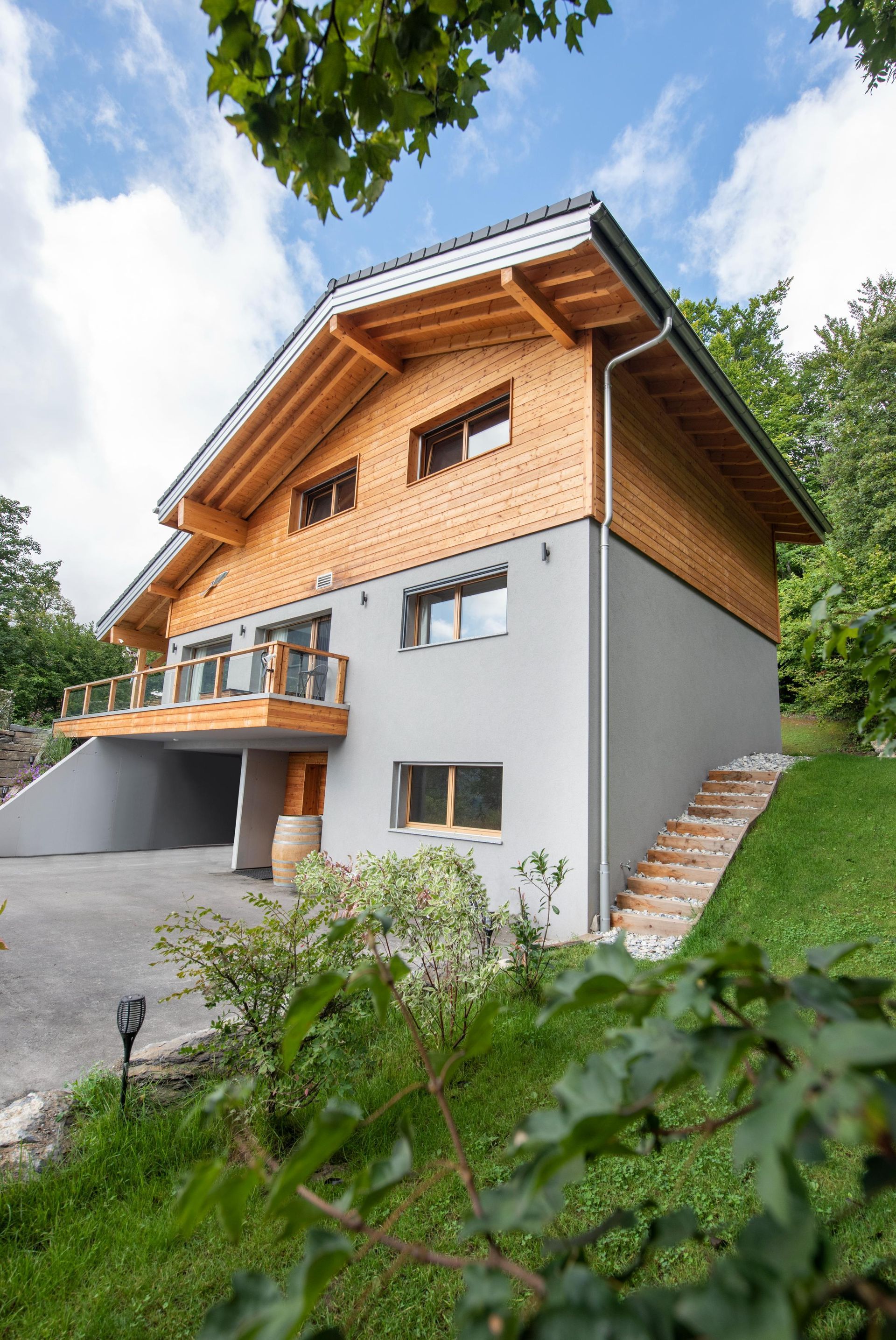 Une grande maison avec un toit en bois est assise au sommet d'une colline herbeuse.