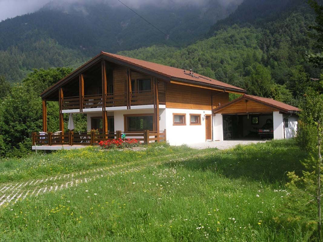 Une grande maison au toit rouge se trouve au milieu d'un champ herbeux.