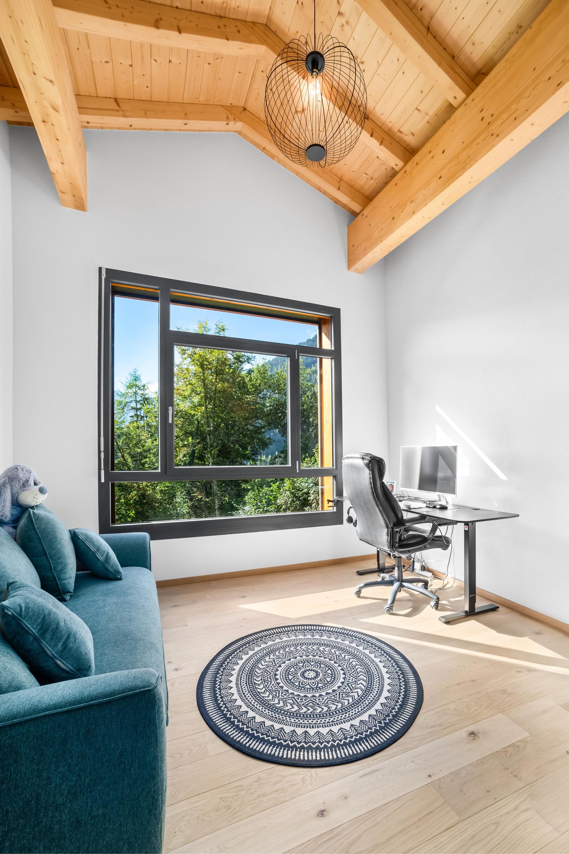 Un salon avec un canapé bleu et un bureau avec un ordinateur dessus.