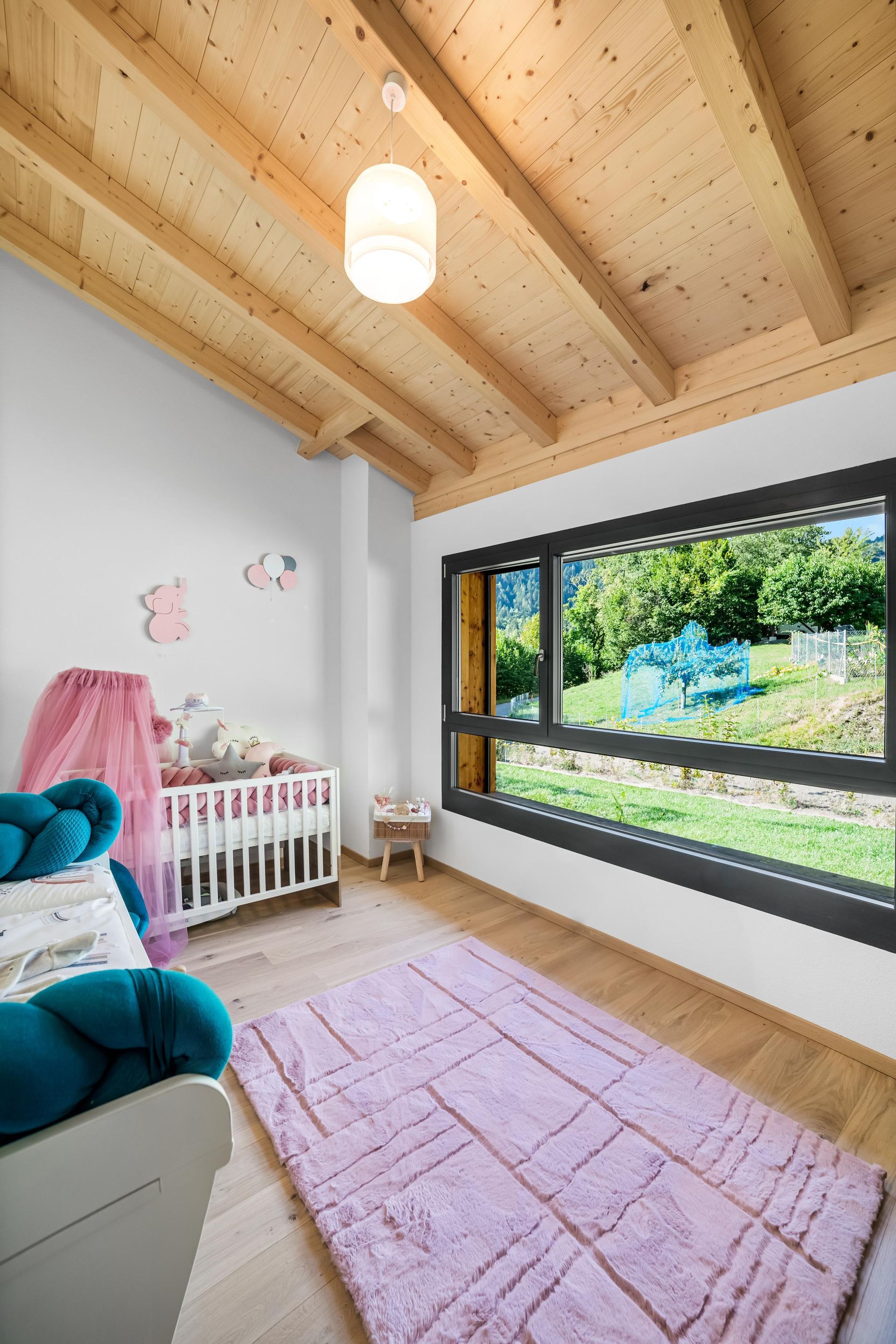 Une chambre avec un berceau, un lit, un tapis et une fenêtre.