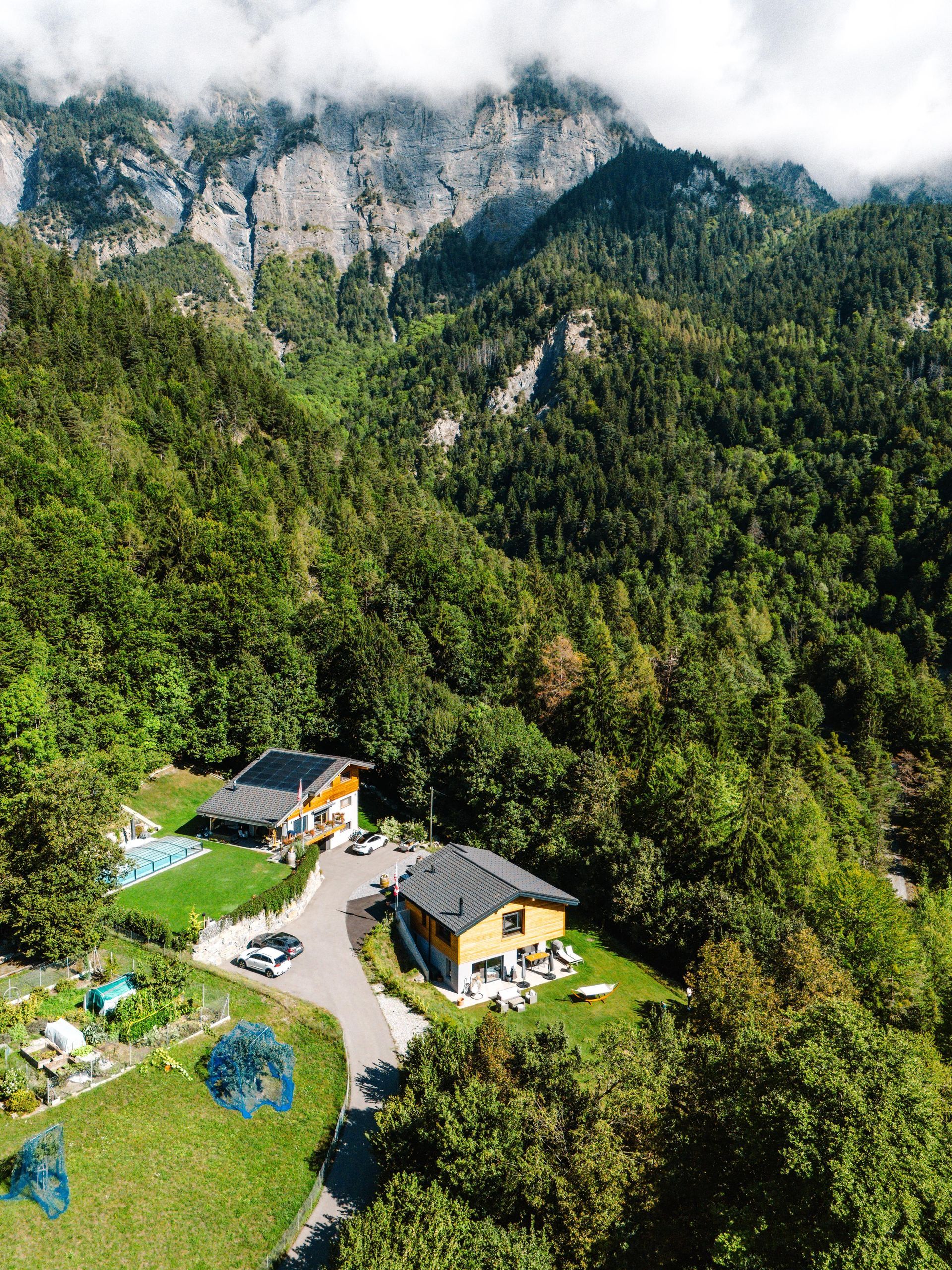 Une vue aérienne d'une maison au milieu d'une forêt avec des montagnes en arrière-plan.