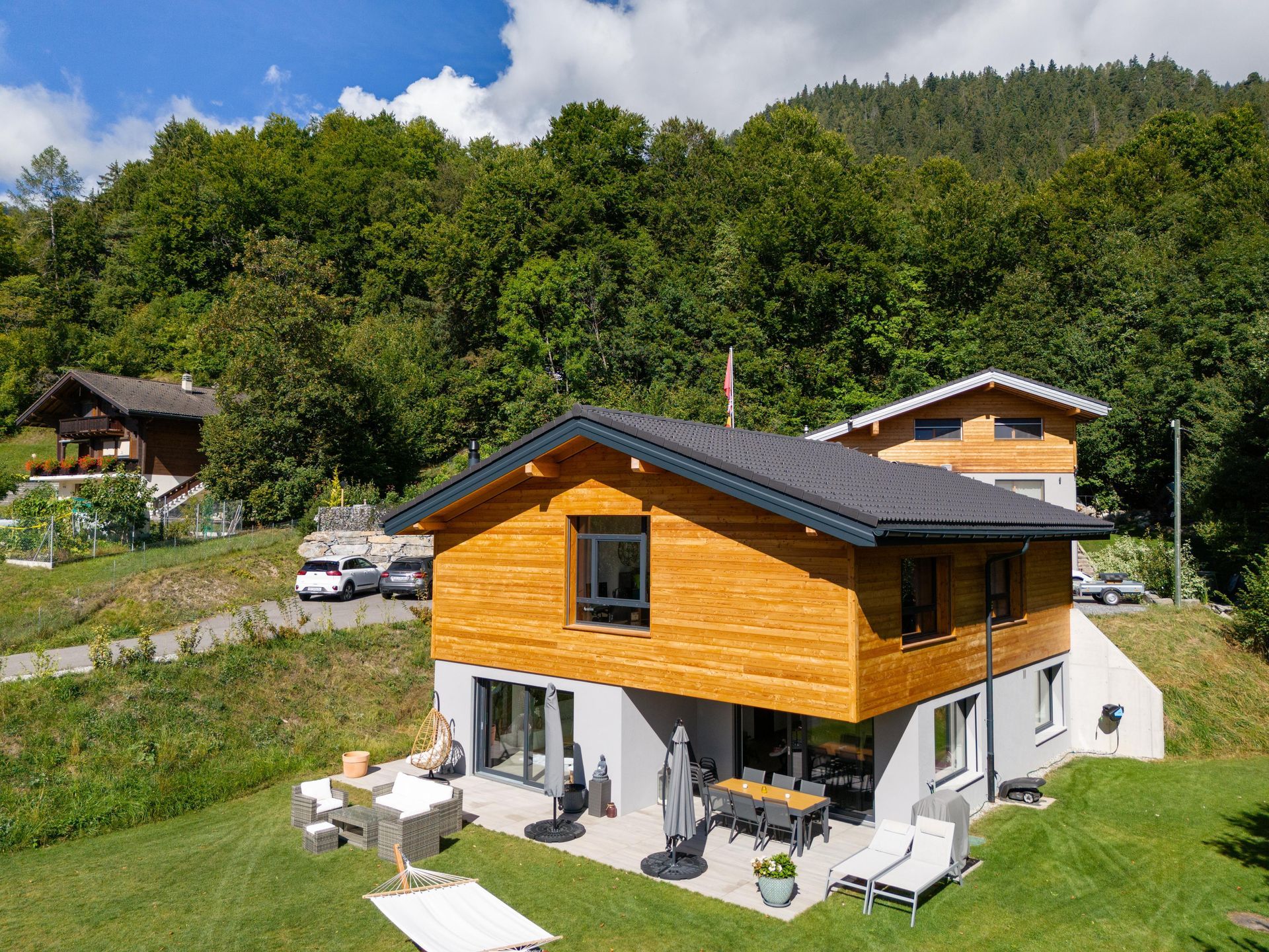 Une vue aérienne d'une maison avec une grande pelouse devant elle entourée d'arbres.