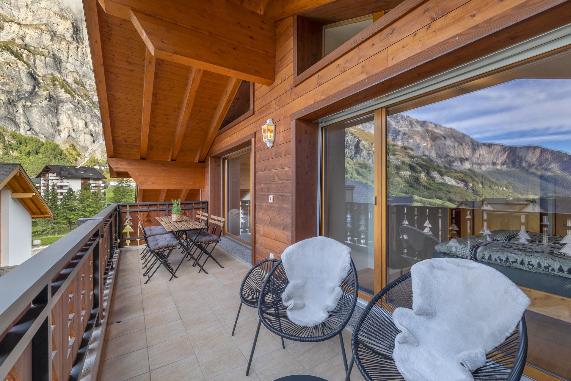 Un balcon avec des chaises et une table avec des montagnes en arrière-plan.