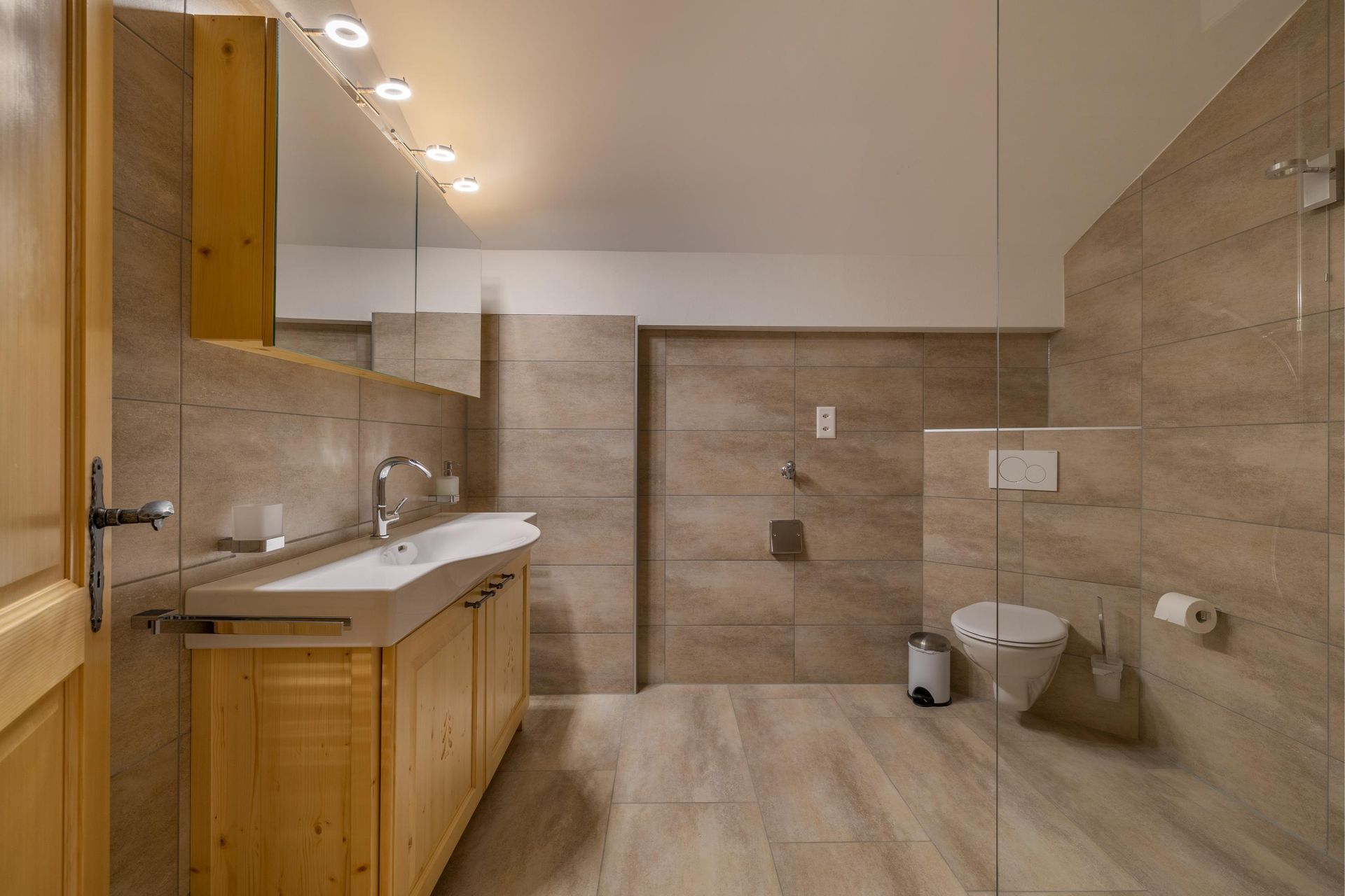 Une salle de bain avec lavabo, WC et douche à l'italienne.